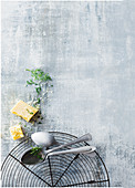 A cooling rack, spoons, Parmesan and dill on a grey background