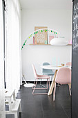 Arc lamp over dining table with upholstered chairs in pastel shades