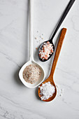 Sea salt, rock salt and Himalayan salt on spoons