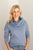 Junge blonde Frau in blauem Pulli mit passendem Schal