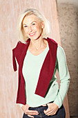 Ältere blonde Frau in hellgrünem Strickpulli, dunkelrotem Pulli über den Schultern