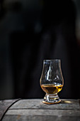 A glass of whisky on a wooden barrel