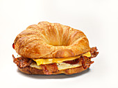 A croissant bagel with bacon, fried egg and cheese