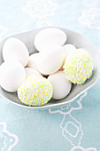 weiße Eier und mit Zuckerperlen verzierte Eier in einer Schale