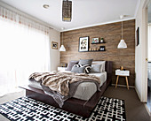 Schlafzimmer in Erdfarben mit Holz verkleideter Wand