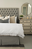 Double bed with button-tufted headboard, chest of drawers and wall-mounted mirror