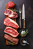 Variety of Raw Black Angus Prime meat steaks Tenderloin fillet mignon, Rib eye, Striploin, Blade, Machete on wooden board and seasoning