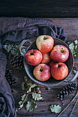 Red apples in a bucket on a rustic wooden table