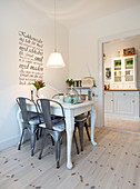 Metal chairs around white dining table below wall decal