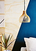 Pendant lamp in front of plywood wall with a blue, geometric pattern