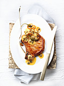A pork chop with an onion and caper sauce