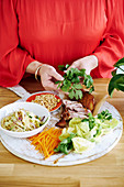 Woman with ingredients for warm Thai-style duck salad