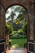 View through arched doorway of palm trees in exotic garden