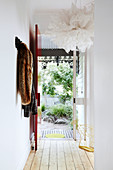 Cloakroom rail and designer lamp in white hallway with wooden floorboards