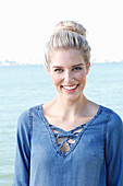 A young blonde woman with a bun wearing a denim blouse