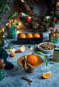 Mandarinen, Mandeln, Trauben, Zimtstangen, Lichterkette und weihnachtlicher Wandkranz