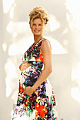 A pregnant woman wearing a floral-patterned, sleeveless summer dress