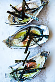 Oysters with algae strips on a bed of salt (close-up)