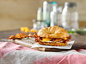 A croissant sandwich with egg, bacon and cheese