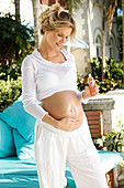 Schwangere Frau reibt sich den Bauch mit Öl ein