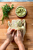 Woman's hands rubbing a raw chicken with herb butter