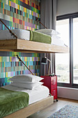 Bunk-beds suspended from wall decorated with colourful wallpaper