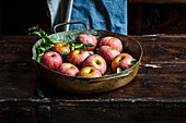 Äpfel in Metallschale auf rustikalem Küchentisch