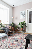 Houseplants, rug and woman sitting on sofa in bright living room