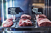 Various beef types (flat iron steak from wagyu beef, ribeye steak) with price tags