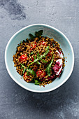 Salad with quinoa, tomato and arugula in bowl on concrete background