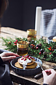 Christmas breakfast table: Woman eating pumpkin pancakes with yogurt cream and currant