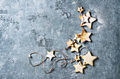 Homemade shortbread star shape sugar cookies different size with sugar powder on thread over blue texture surface