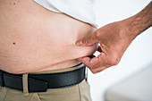 Man squeezing fat at waist