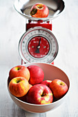 A bowl of red apples and one on an old-fashioned pair of kitchen scales
