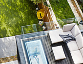 Sofa on roof terrace with glass balustrade and view of garden