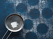 Icing sugar sifter on blue concrete background