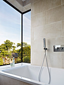 Bathtub in modern bay window with view of garden