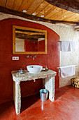 Beton-Waschtisch mit Aufsatzbecken im Badezimmer mit rot gestrichenem Boden und Wand