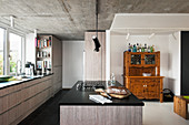 Moderne Küche mit grauen Fronten, Betondecke und altem Buffetschrank