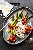 Asparagus with chicken breast and grapes on a baking tray