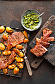 Steak on a baking tray with rosemary potatoes and salsa verde