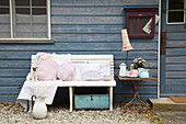 Various cushions with hand-sewn covers on bench outside wooden house