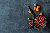 Fresh berries in a pan with apricots next to it