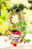 A wreath of wild strawberry stems hung over a glass bowl filled with water and rose petals