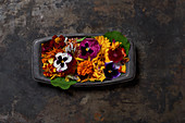 Various flowers in dark casserole dish