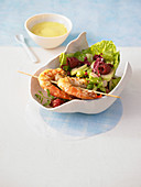 A colorful salad with raspberries, a prawn skewer and champagne dip