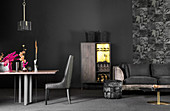 Back velvet sofa, stool, cabinet and dining table and chair in front of black wall