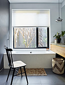 Chair in front of bathtub in bathroom with window