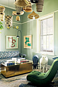 Easy chair with green upholstery, animal sculptures, coffee table and sofa in lounge with green-painted walls