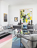 Abstraktes Gemälde im Wohnzimmer mit grauen Möbeln und Pastellfarben